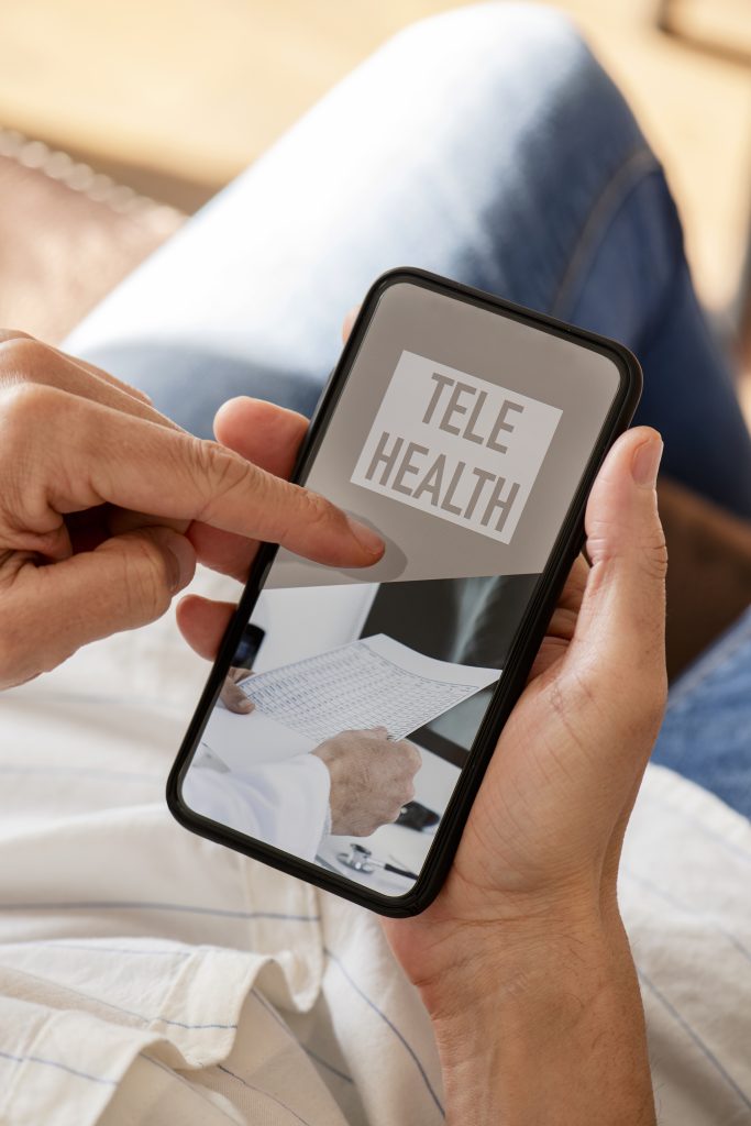 closeup of a young caucasian man, sitting comfortably in a couch, using his smartphone, with the text telehealth on its screen